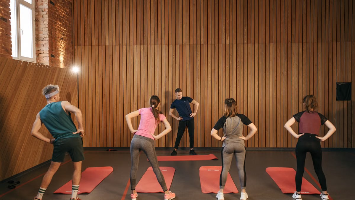 People stretching on yoga mats during a fitness class indoors.